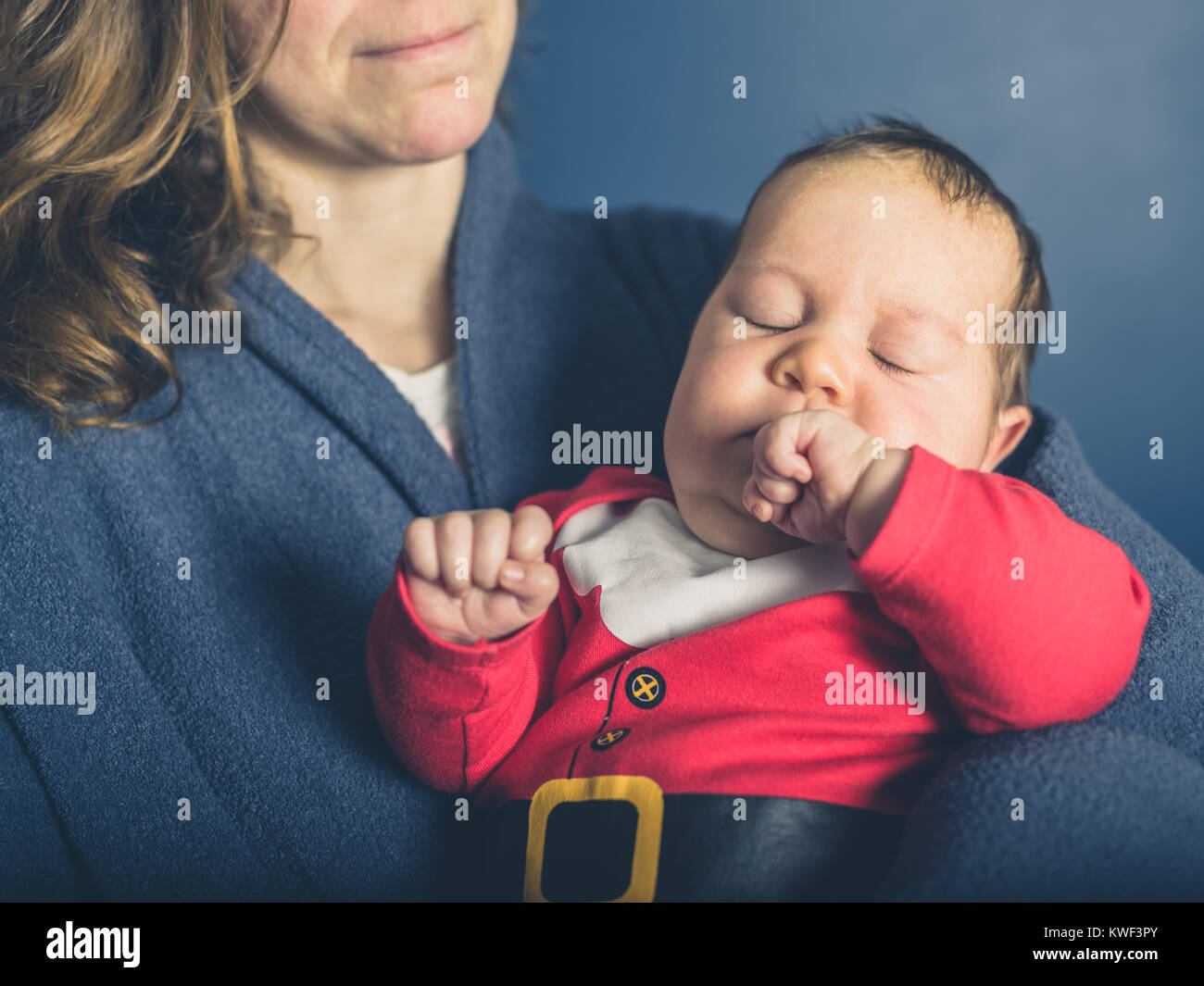 Une jeune mère est tenant un bébé portant un costume de Père Noël Banque D'Images