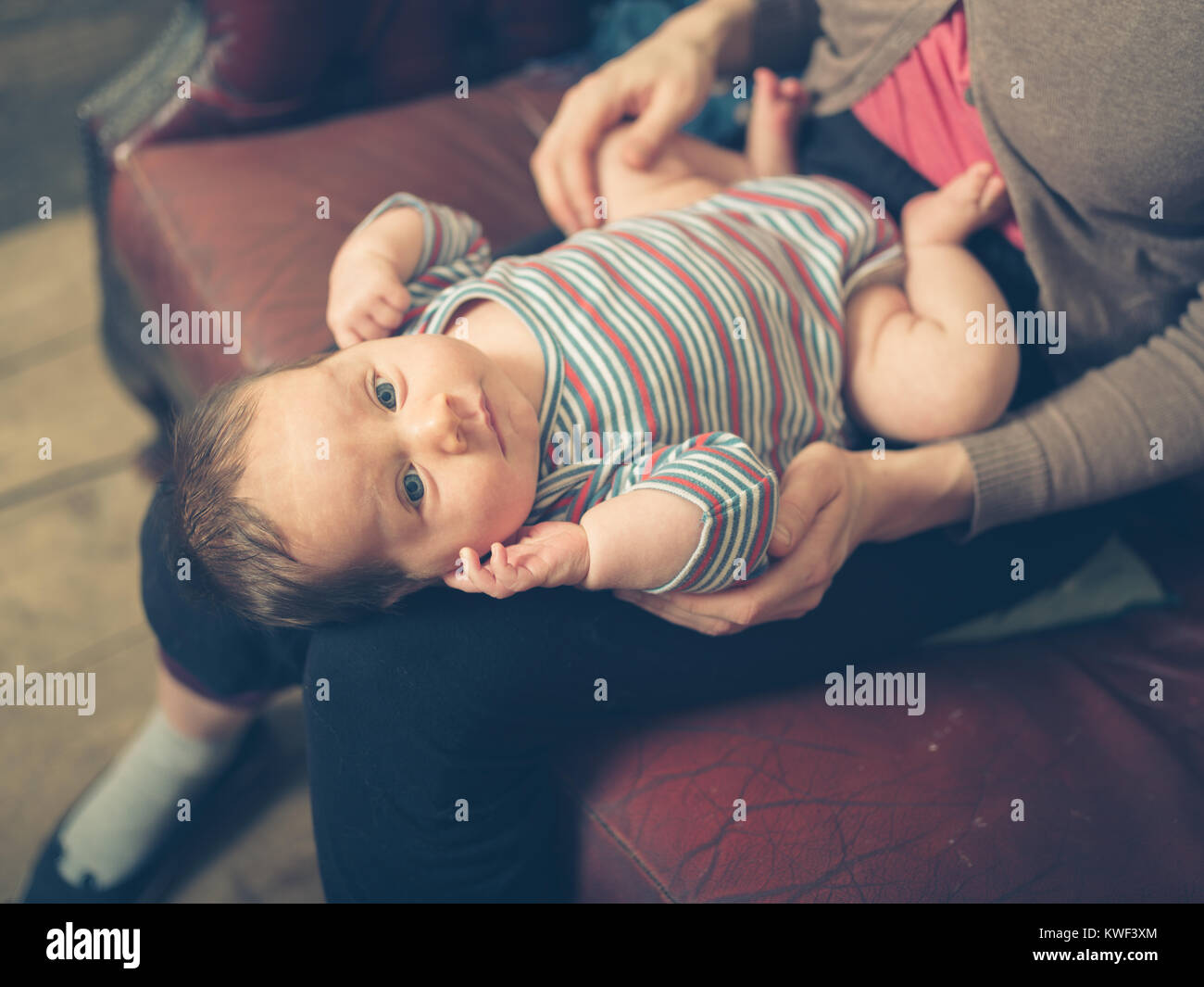 Un bébé heureux sur les genoux de sa mère à la maison Banque D'Images