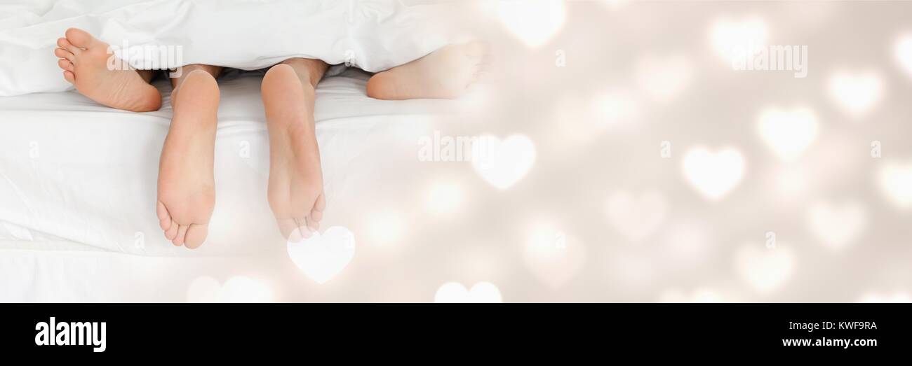 Pieds de couple dans le lit avec coeur de transition amour de Valentin Banque D'Images