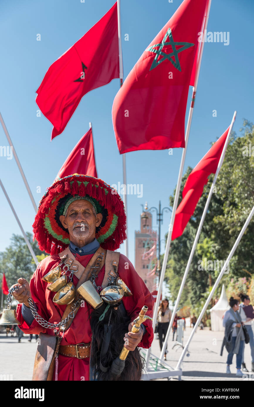 Vendeur d'eau traditionnels et la Koutoubia avec drapeau marocain. Banque D'Images