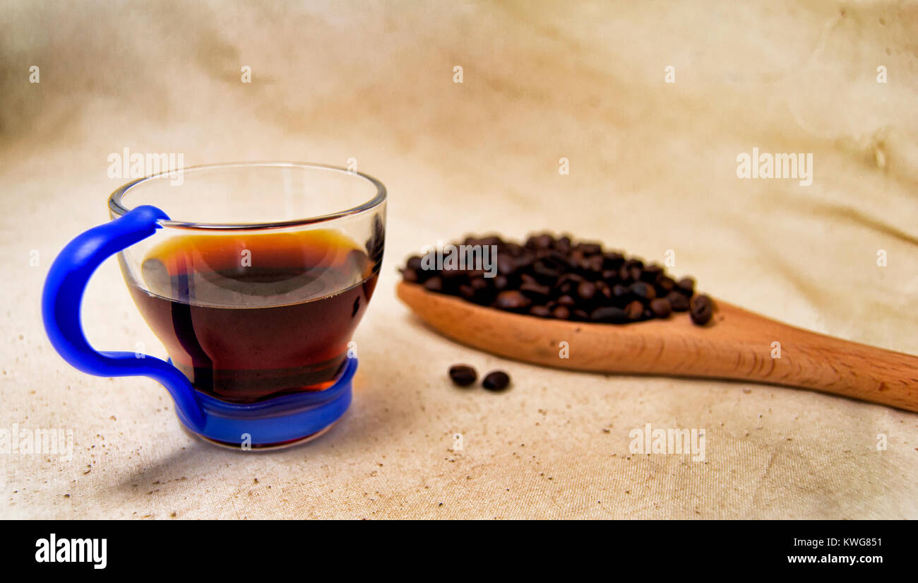 Soft focus d'une tasse de boisson énergétique infusion et les grains de café sur une cuillère en bois avec un fond brut. pour detox et concept sain Banque D'Images