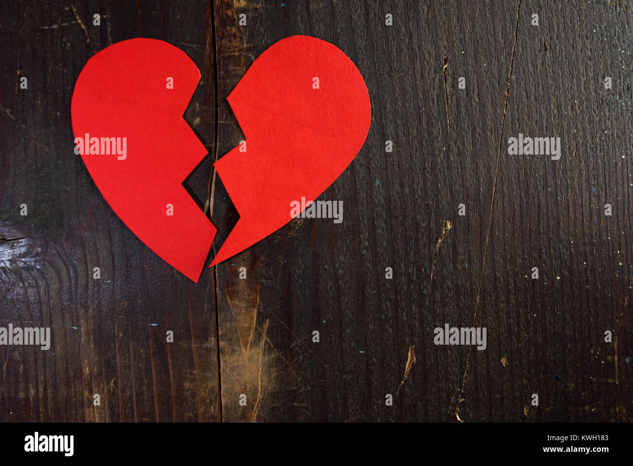 La rupture d'un coeur déchiré de papier rouge sur un fond de bois Banque D'Images