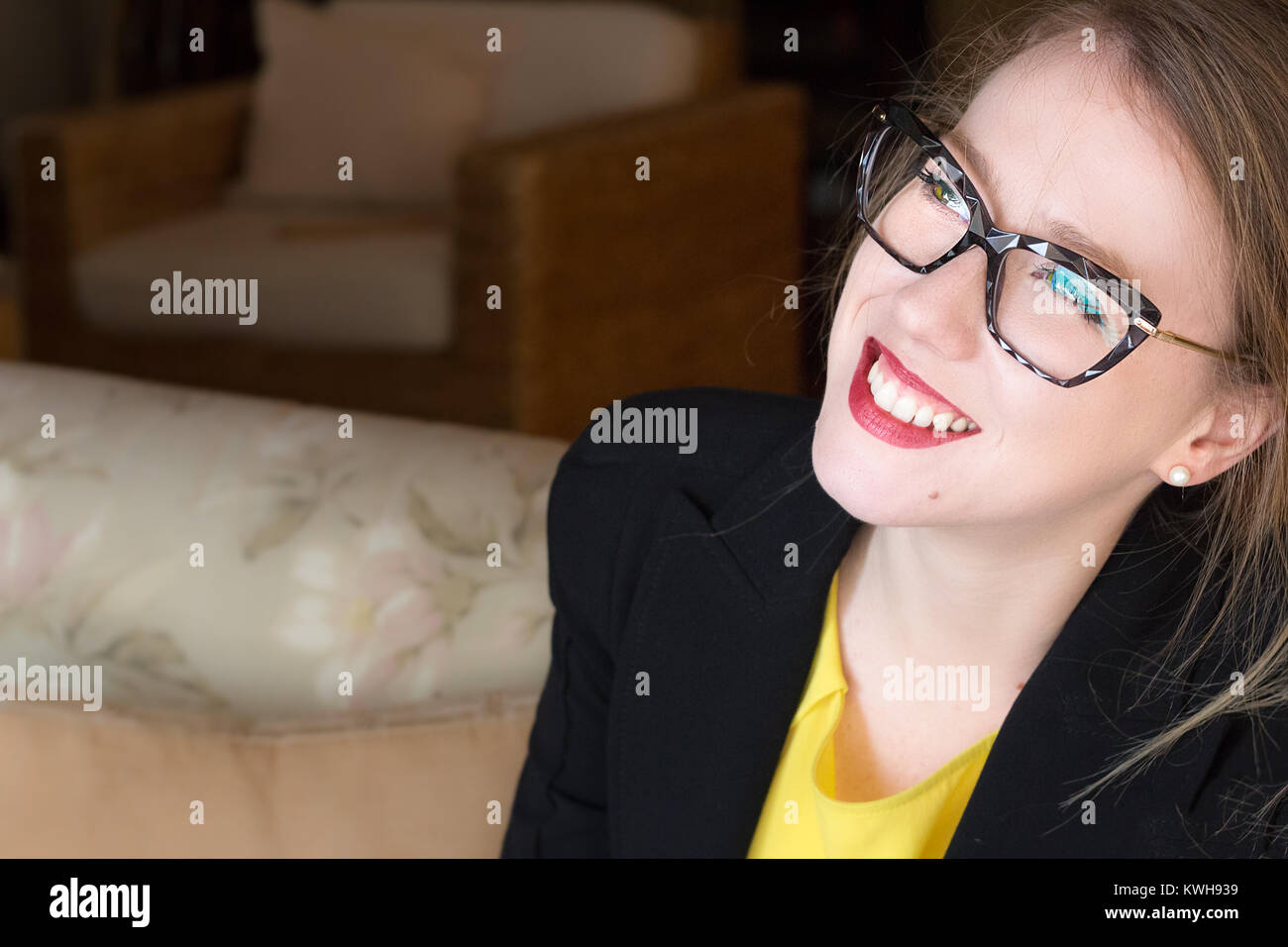 Portrait d'une jeune femme blonde portant des lunettes à la recherche de là, souriant, heureux, libre, lumière naturelle, à l'intérieur. Banque D'Images