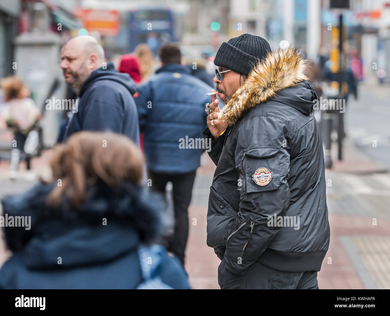 Homme noir habillé en vêtements d'hiver de fumer une cigarette en hiver en Angleterre, Royaume-Uni. Banque D'Images