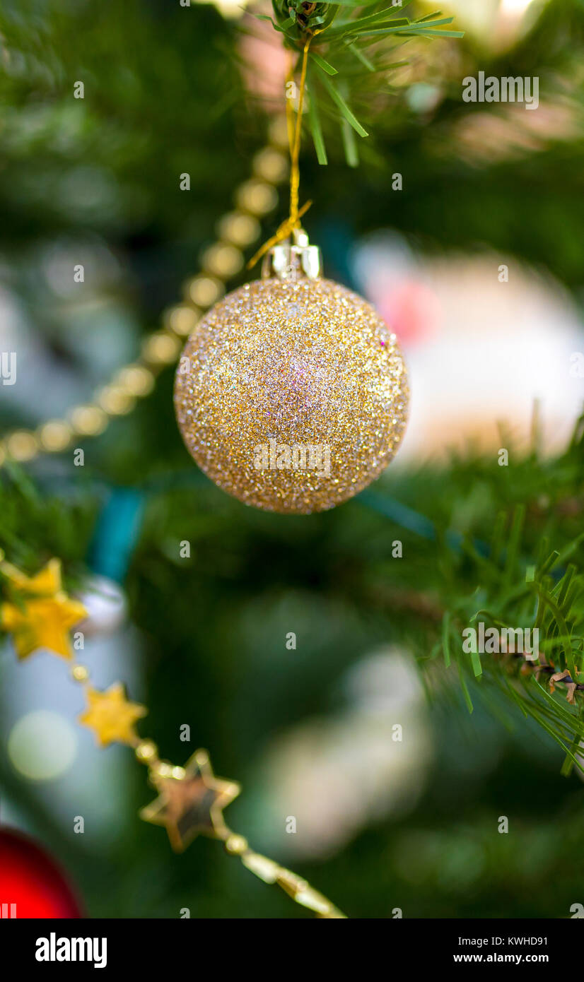 Et mousseux paillettes or brillant bauble hanging sur un arbre artificiel Chritmas festive enveloppée avec étoiles d'or Banque D'Images