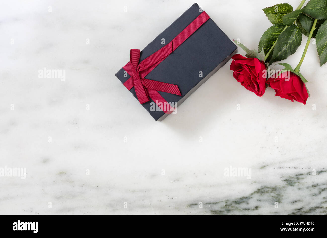 Roses rouges et sombre boîte-cadeau sur fond noir en marbre dans la mise à plat Banque D'Images