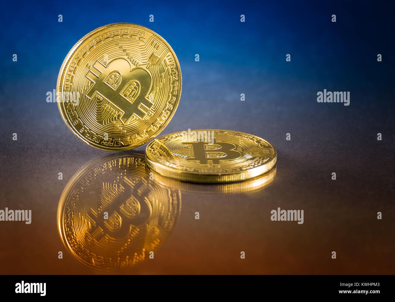 Cryptocurrency couleur physique pièces bitcoin. Deux golden avec bitcoin et bleu sur fond orange. Banque D'Images