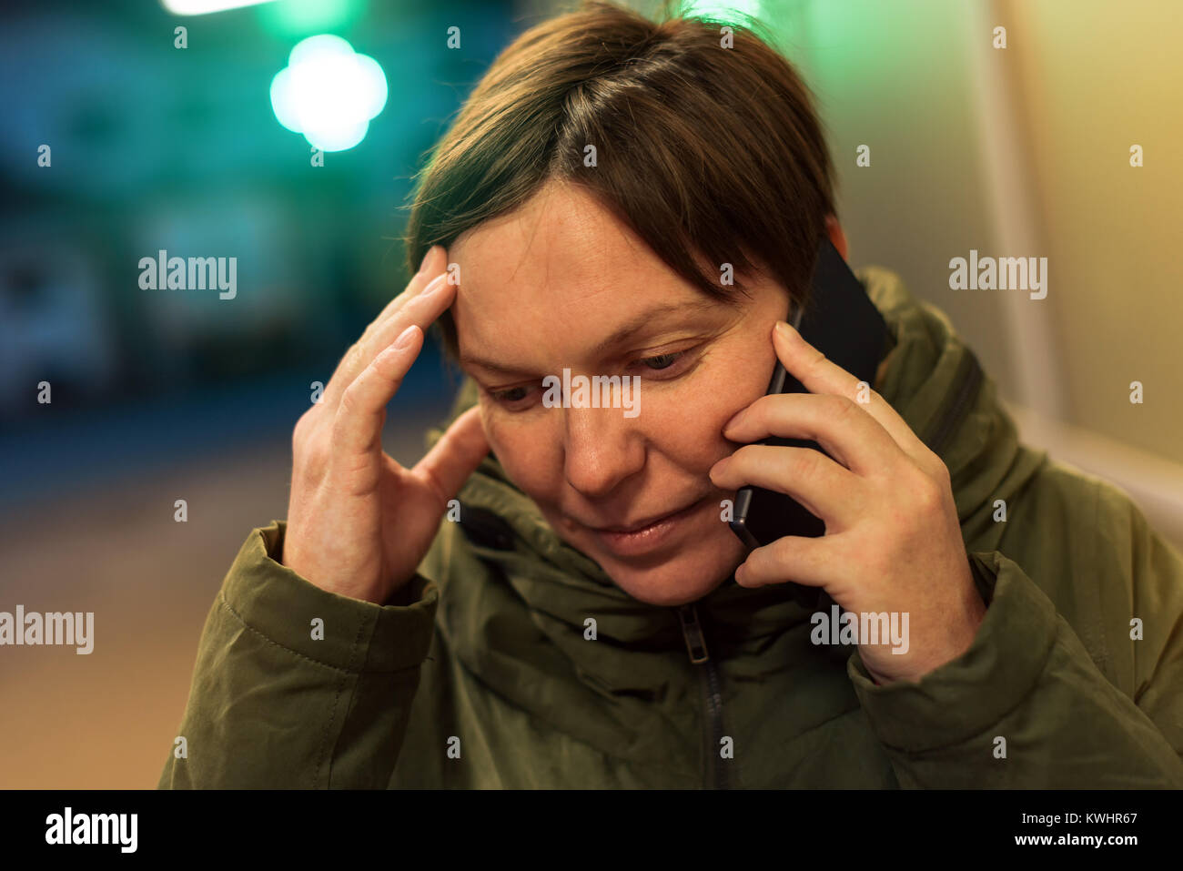 Worried Woman talking on mobile phone in front of pharmacie de nuit. Femelle adulte à l'aide de téléphone pour consulter votre médecin avant l'achat de médicaments dans Banque D'Images