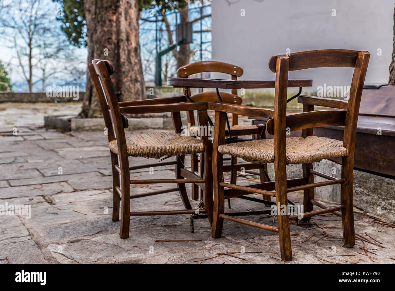 Une table en bois et 3 chaises style vintage, dans un carré en pierre au village de Kissos sur Pelion Grèce Banque D'Images