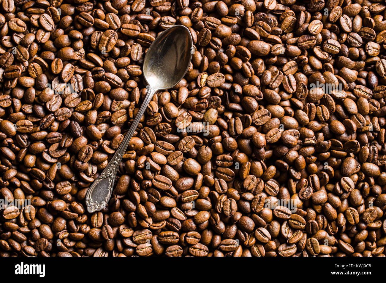 Les grains de café torréfiés et cuillère en argent. Banque D'Images
