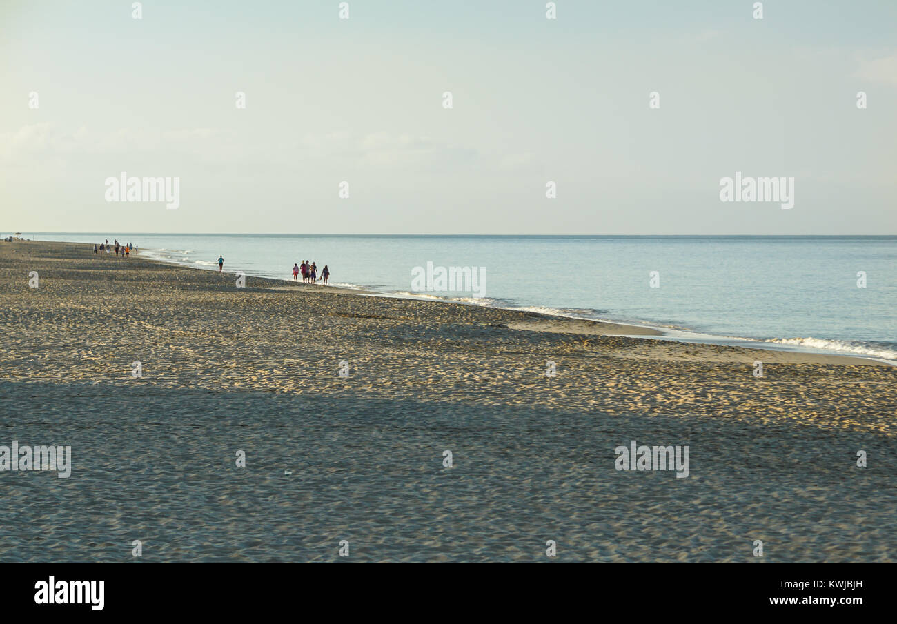 Les gens qui marchent sur la plage au lever du soleil, beau ciel nuageux reflétée sur la plage Banque D'Images