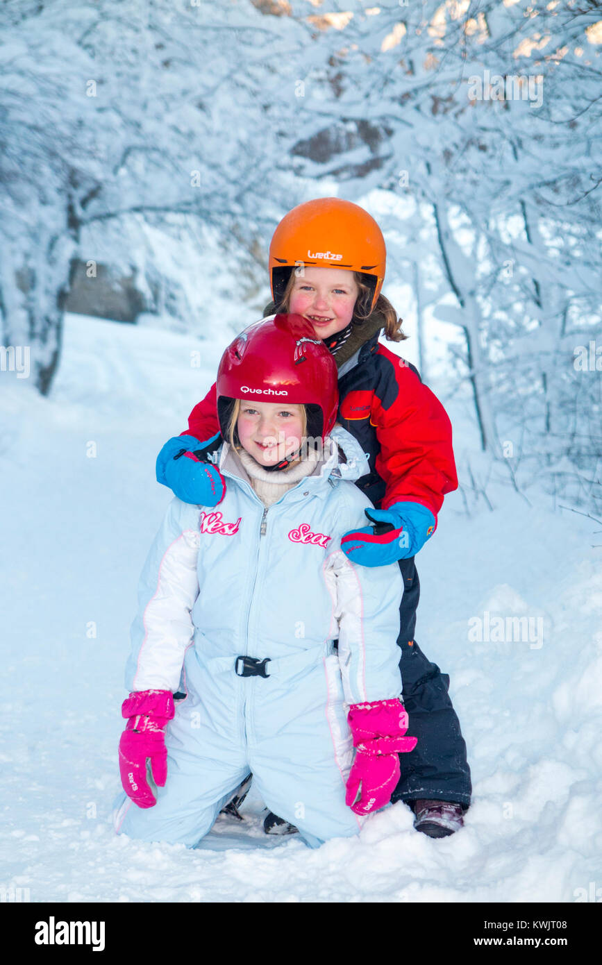 Filles, sœurs, âgés de 5 et 7 ans, et portant des casques de ski freecycle pour la sécurité, profitez de l'hiver la neige dans leur seconde main, élégant & charity shop wear Banque D'Images