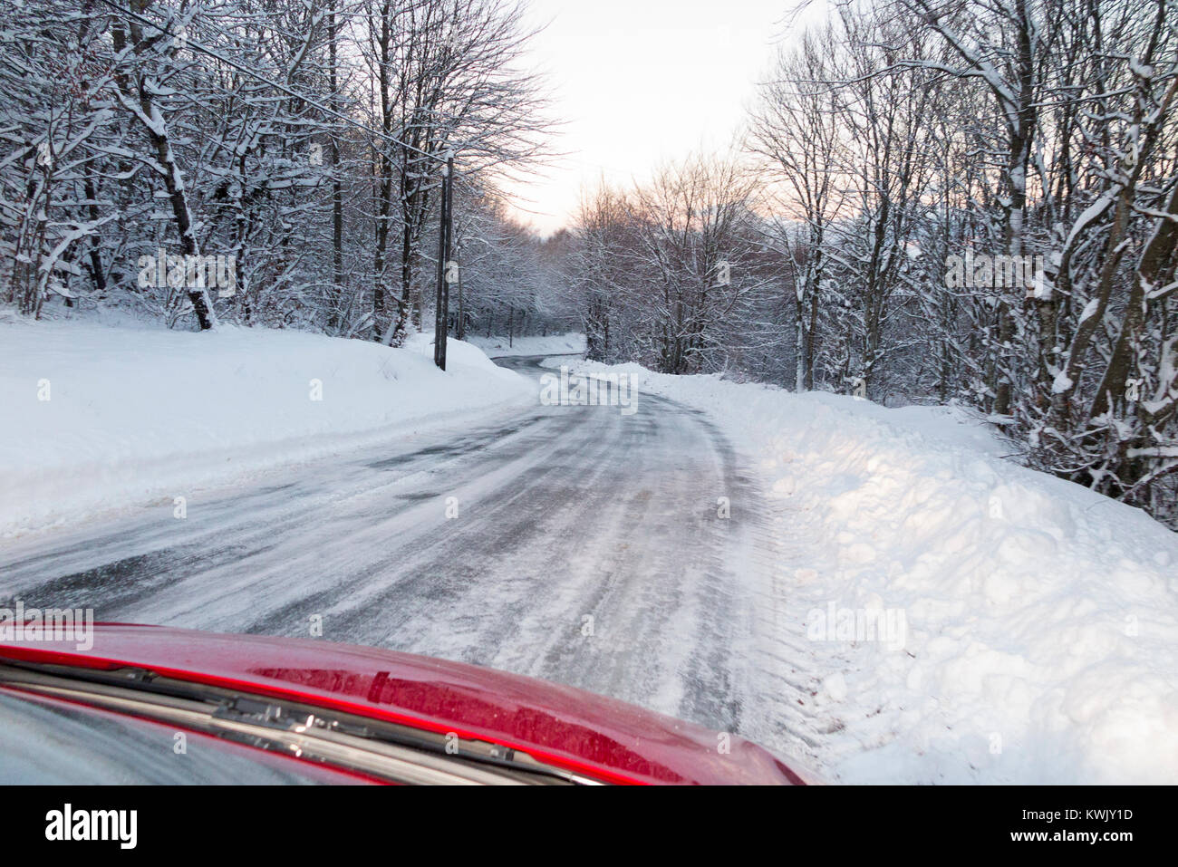 Neige glissante recouverte de glace alpine française country road, avec de la glace, après un blizzard, vu à travers le pare-brise de l'intérieur de la voiture à la tombée de la nuit. Alpes Banque D'Images