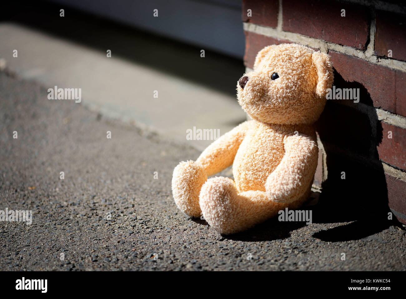 Teddy matériel se trouve sur le terrain, photo symbolique traumatisme de l'enfance et de pouvoir, Ein sitzt auf dem Stoff-Teddy Symbolfoto Kindheitstrauma, Boden und Gewa Banque D'Images