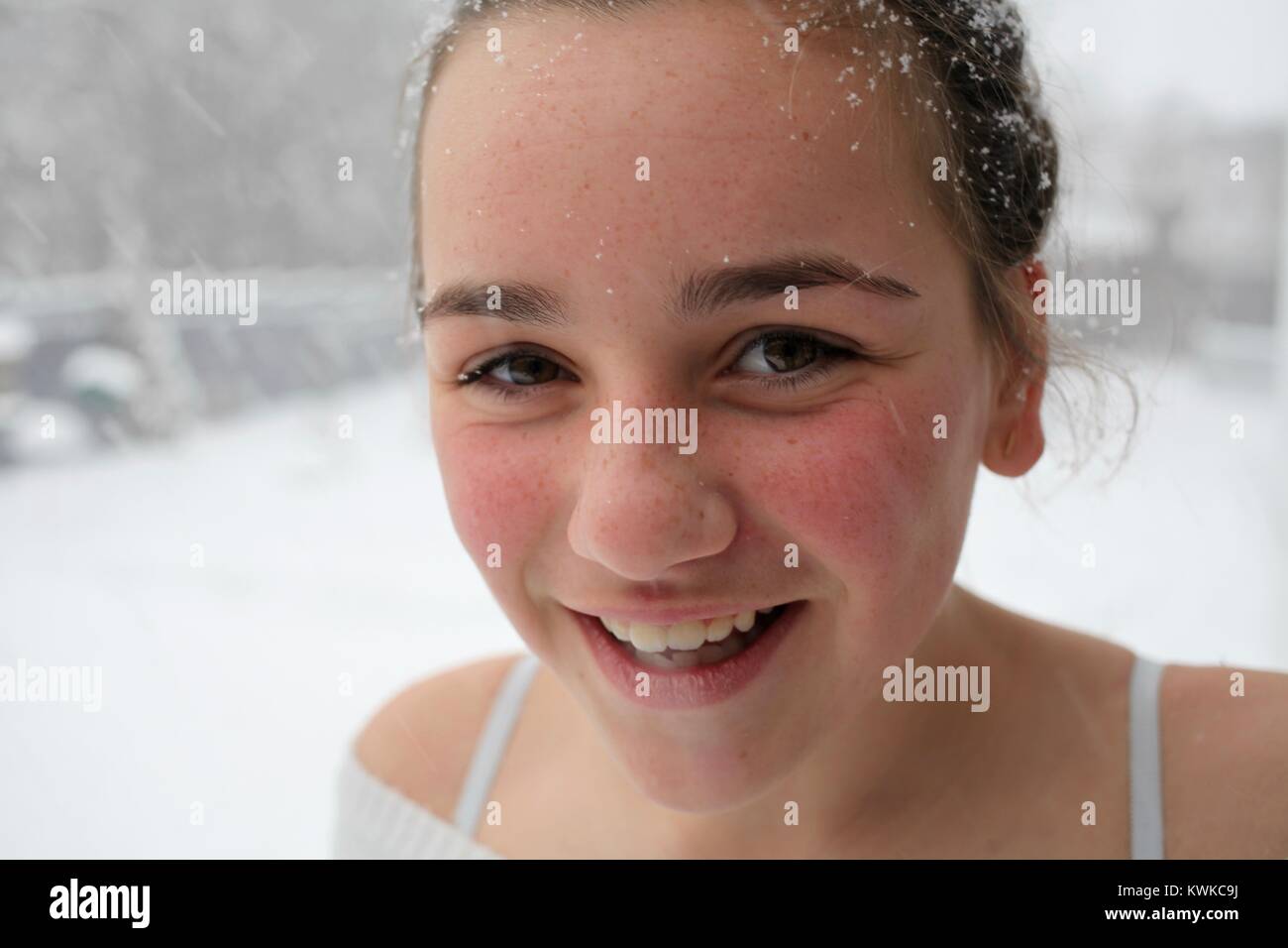 Portrait of a young woman smiling as snow falls dans les cheveux et autour de son visage Banque D'Images