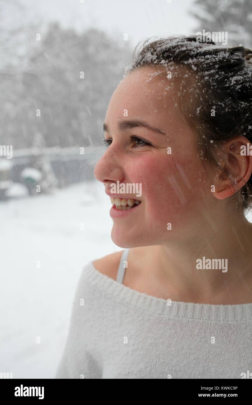 Portrait of a young woman smiling as snow falls dans les cheveux et autour de son visage Banque D'Images