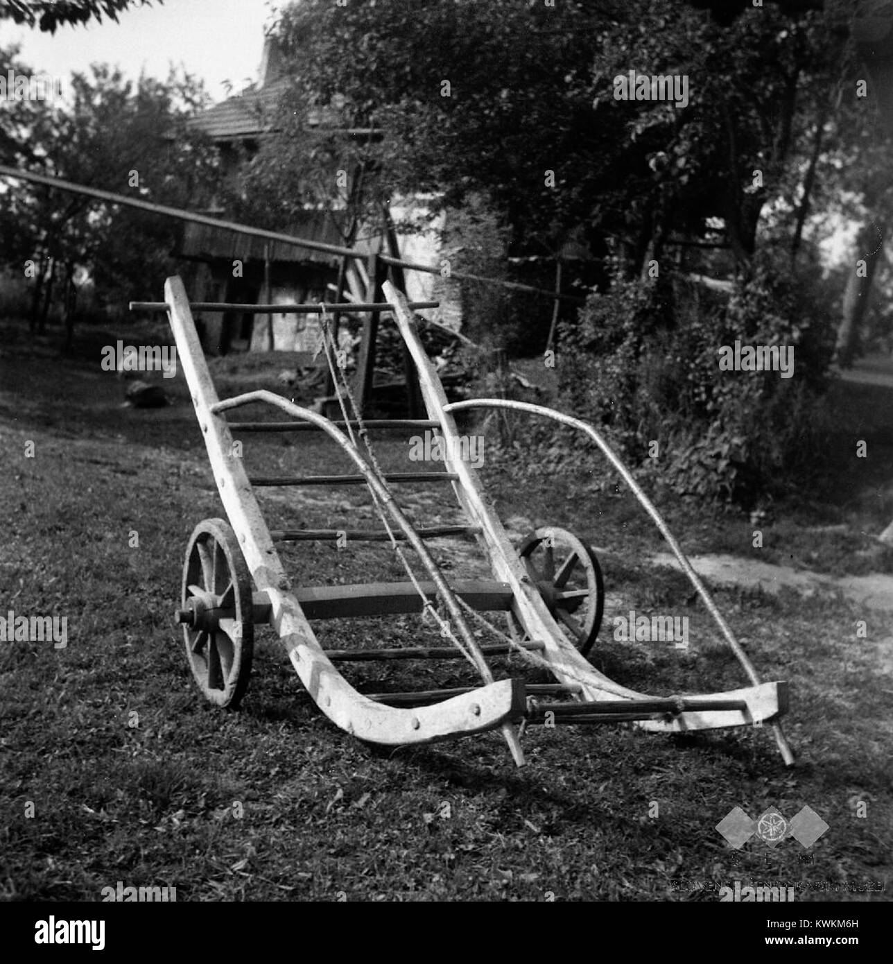 Une photo de 1957 à Visejec montre des travailleurs utilisant un râteau « šatrga » pour rassembler l'herbe tondue en tas pour la charger sur un wagon, illustrant les méthodes traditionnelles slovènes de fenaison. Banque D'Images