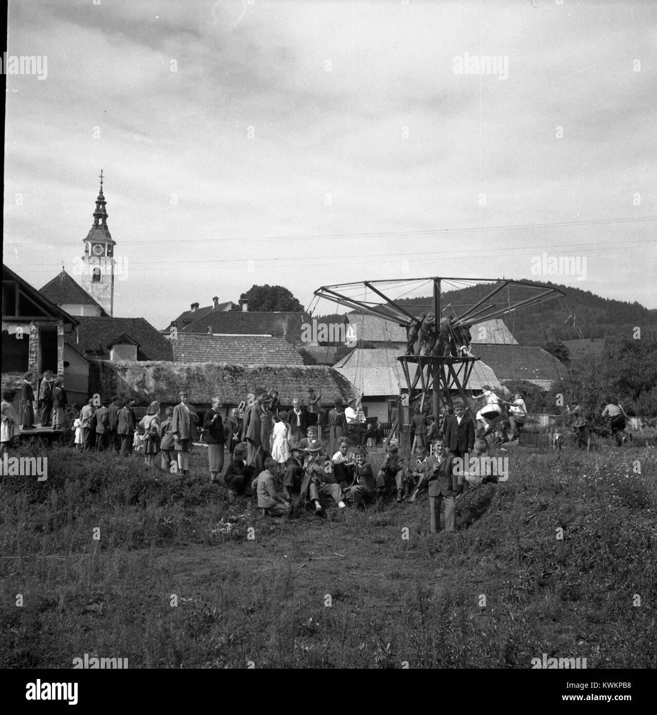 La photographie de 1950 montre un ''Ringlspil'' (carrousel) à un Vid, Slovénie, avec des coureurs profitant d'une attraction de foire typique de la culture d'amusement européenne d'après-guerre. Banque D'Images