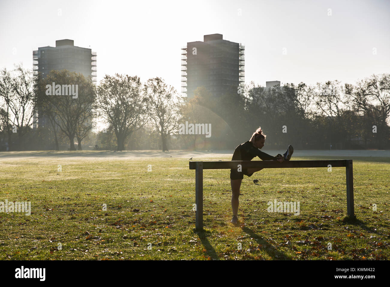 De toute la longueur de la jambe sur l'équipement d'exercice contre les bâtiments au parc en journée ensoleillée Banque D'Images