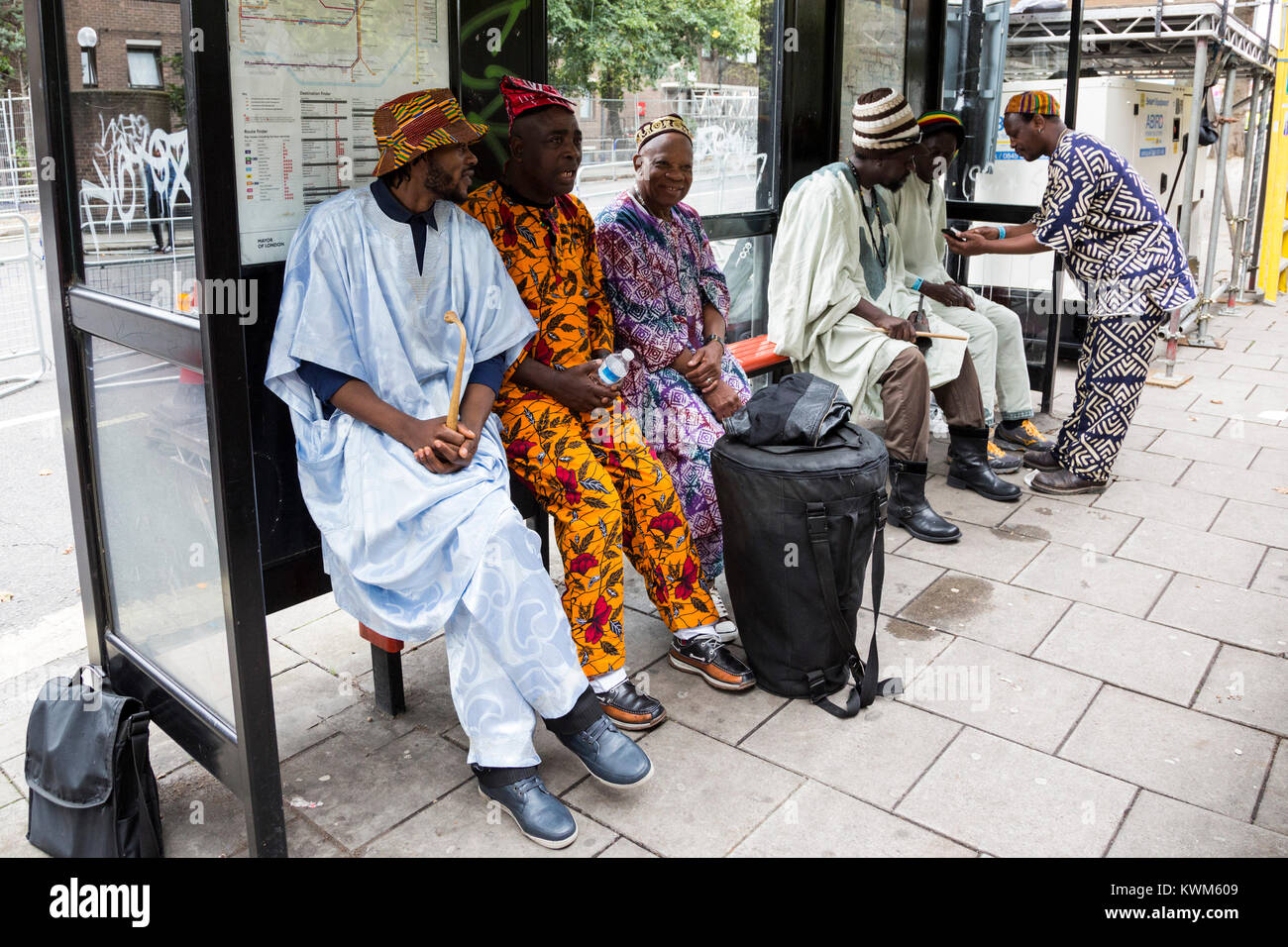 Les hommes vêtus de costumes africains à un arrêt d'autobus en attendant le défilé du carnaval de Notting Hill, Londres, Angleterre, Royaume-Uni Banque D'Images