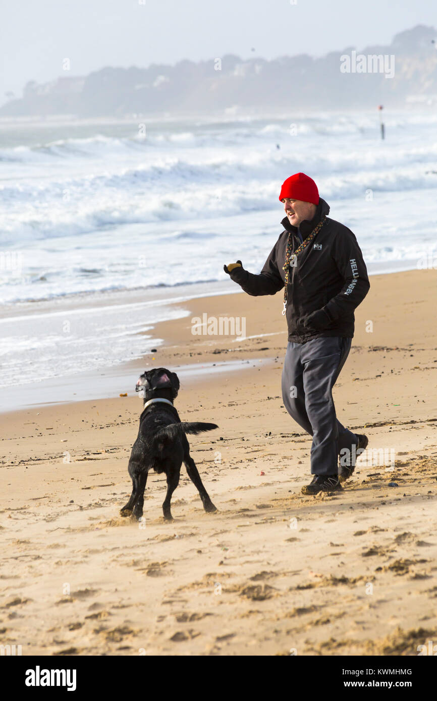 Bournemouth, Dorset, UK. 4 janvier, 2018. Météo France : Jour de vent à Bournemouth. L'homme joue avec son chien sur la plage avec une mer agitée derrière Crédit : Carolyn Jenkins/Alamy Live News Banque D'Images