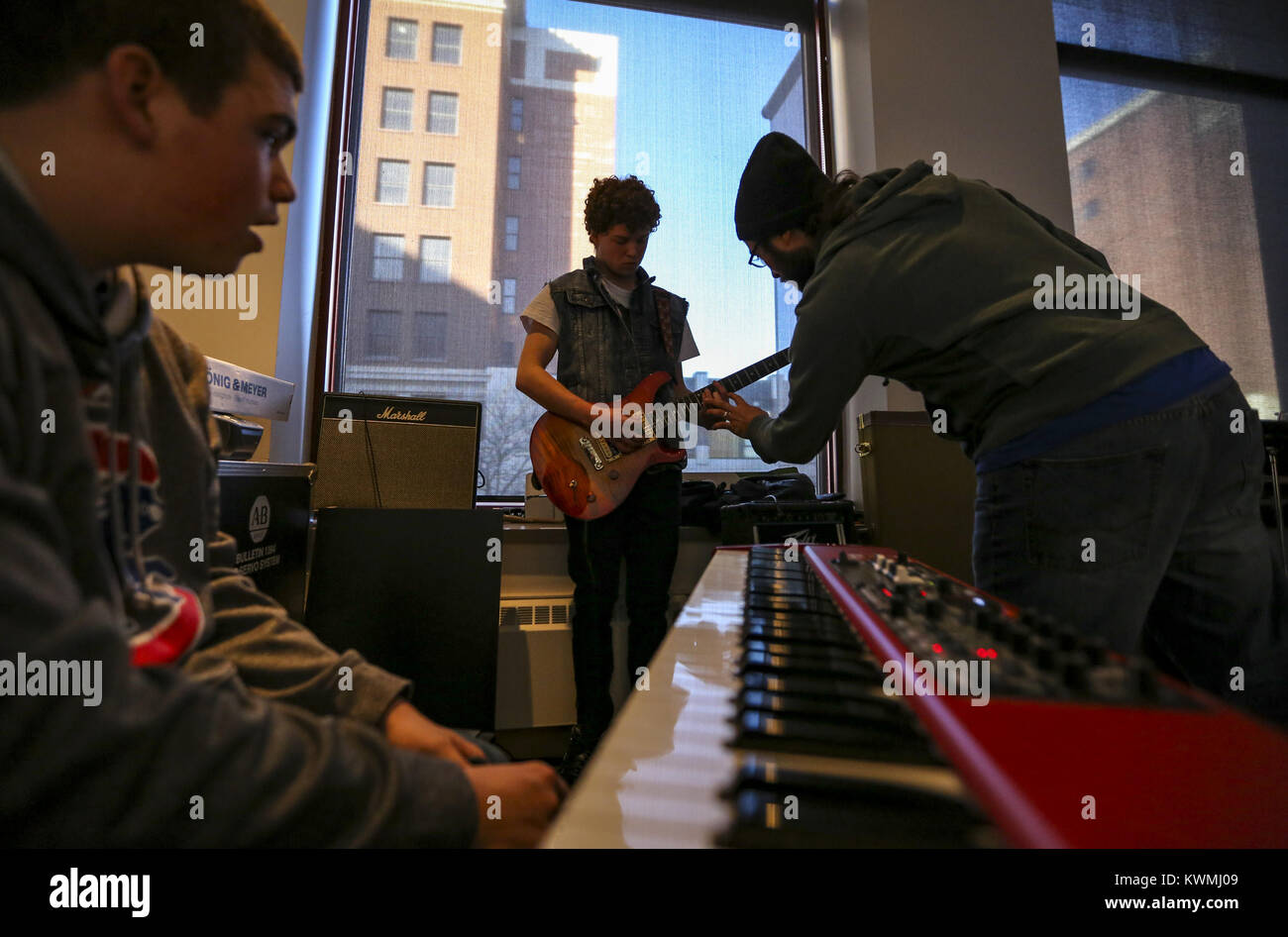 Davenport, Iowa, États-Unis. Dec 27, 2016. Leasman Randy instructeur de Davenport vient en aide à Michael Osborne, 16 ans, de Bettendorf avec sa guitare tandis que le claviériste Ethan bon, 16 ans, de Bettendorf prend un repos à l'expérience musicale dans la construction de la rivière Davenport le Mardi, Décembre 27, 2016. Le Blues de l'hiver annuel instrumentales et vocales caractéristiques du programme des ateliers, ainsi qu'une concentration sur la composition et l'improvisation du blues. Les sessions sont ouvertes aux musiciens âgés de 8-18 et exécuter du lundi au jeudi avant de conclure dans un blues jam dans la chambre Redstone le vendredi. (Crédit Image : © Andy Abeyta Banque D'Images