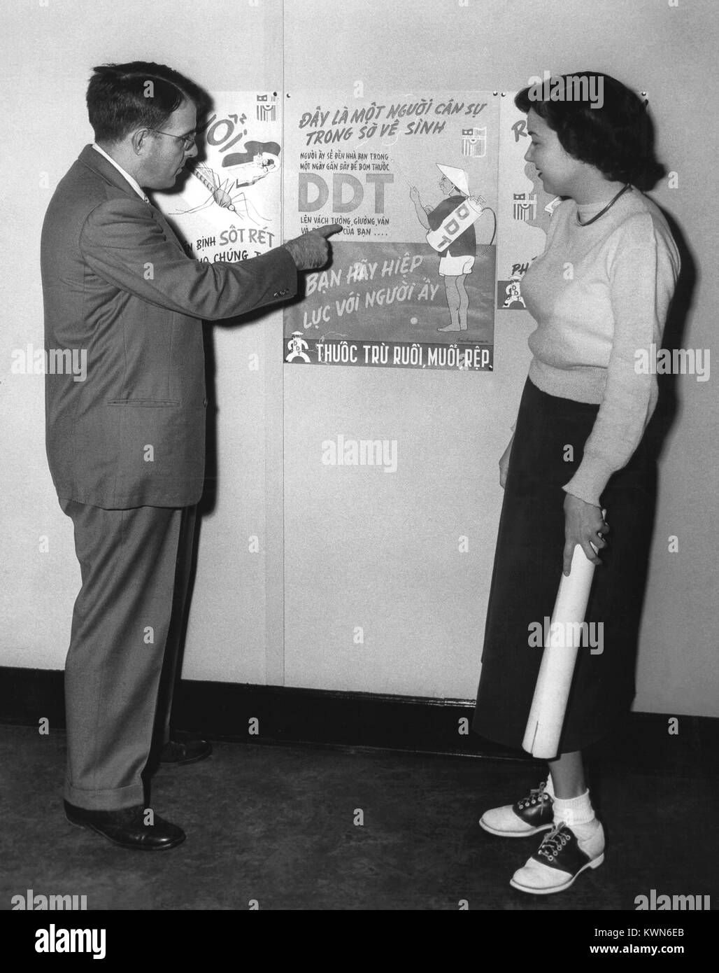 Cette photographie montre l'entomologiste médical CDC Dr Harry D. Pratt décrivant un poster DDT utilisé dans un programme de lutte contre le paludisme, 1958. Le Dr Harry D. Pratt, entomologiste médical avec le Centre des maladies transmissibles, les services de santé publique, indique Mme Martha York un Poster DDT utilisé dans une lutte contre le paludisme, programme parrainé par l'Administration de la coopération économique en Indochine. Image courtoisie CDC. Banque D'Images