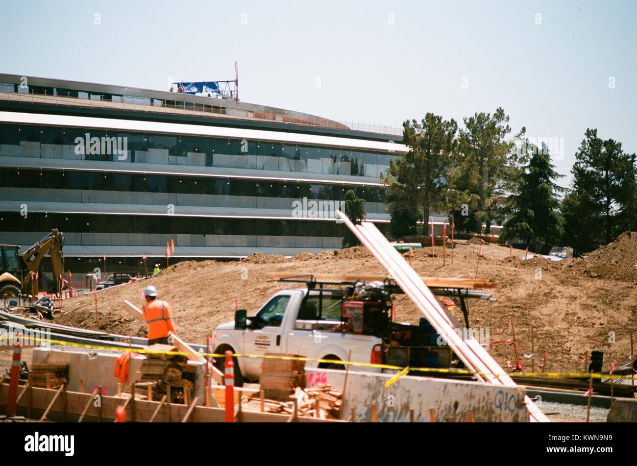 Les travailleurs de la construction, la manutention du bois d'avec les autres travailleurs visible sur le toit du bâtiment principal, à l'Apple Park, connu familièrement comme "le vaisseau spatial", le nouveau quartier général d'Apple Inc dans la Silicon Valley ville de Cupertino, Californie, 25 juillet 2017. Banque D'Images