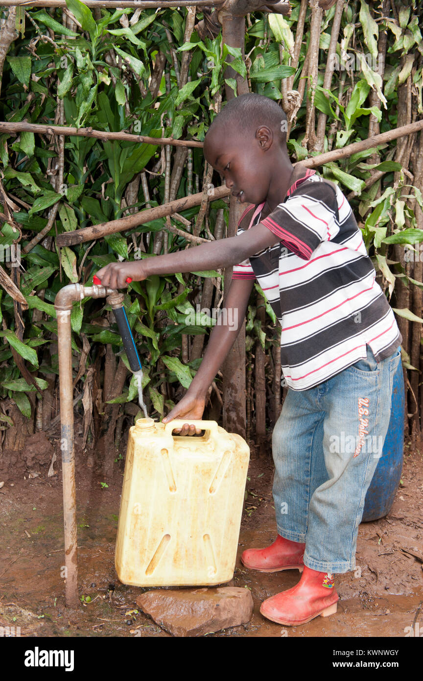 La collecte d'un enfant rwandais de contenant de l'eau d'un tuyau en nouvelle initiative sur l'eau Banque D'Images