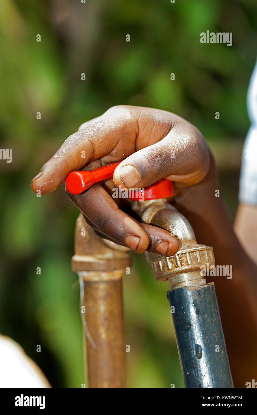 Personne tournant sur un robinet d'eau fournissant des ressources en eau potable au Rwanda l'Afrique. Banque D'Images