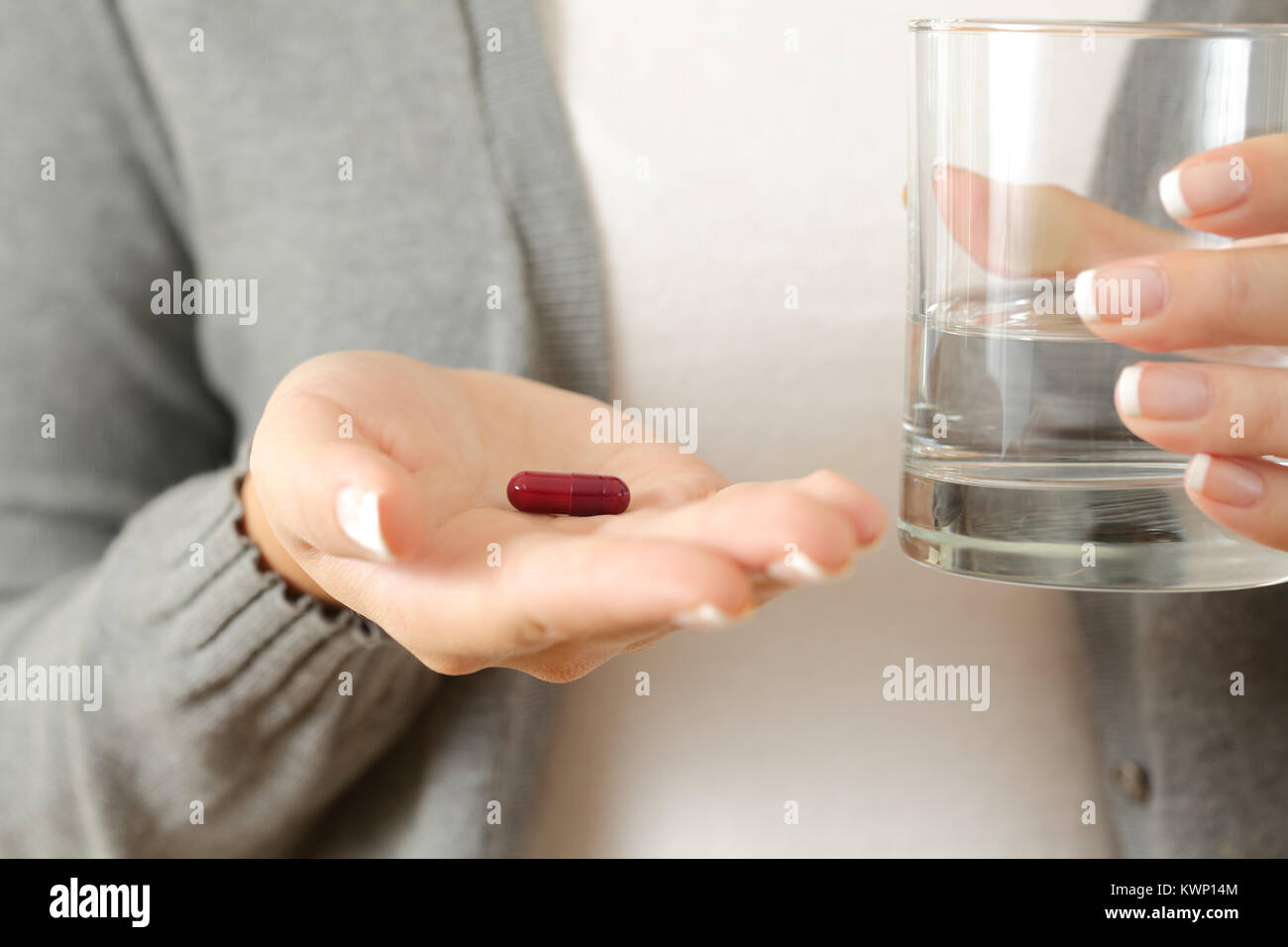 Vue avant close up of a woman holding palm une capsule et un verre d'eau Banque D'Images