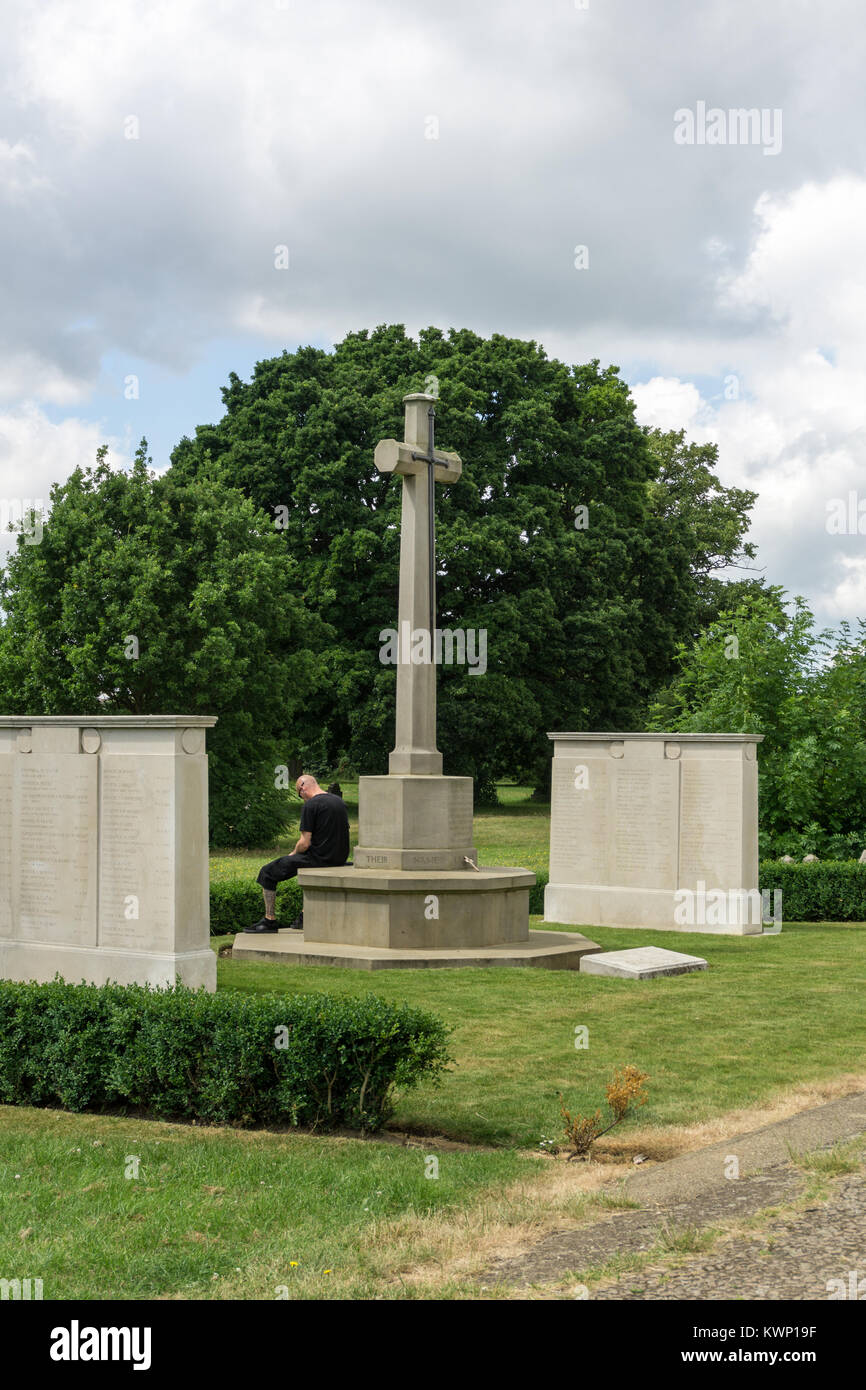 Un homme habillé en noir se trouve dans la contemplation tranquille par un mémorial de guerre ; Cimetière Route de facturation, Northampton, Royaume-Uni Banque D'Images