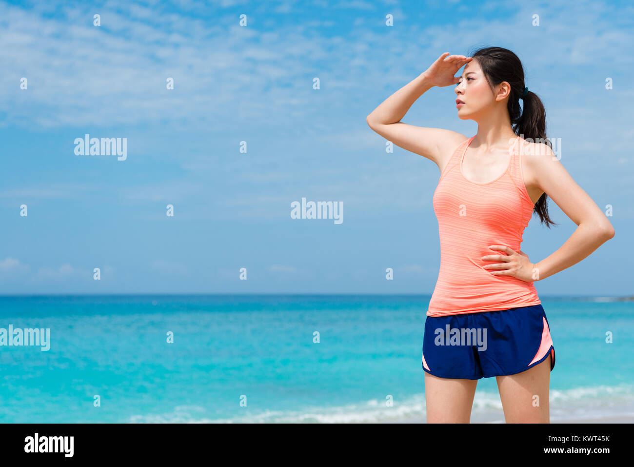 Belle forme physique femelle runner standing on beach à destination du paysage lorsqu'elle a terminé l'exécution de la formation pendant les jours ensoleillés. Banque D'Images