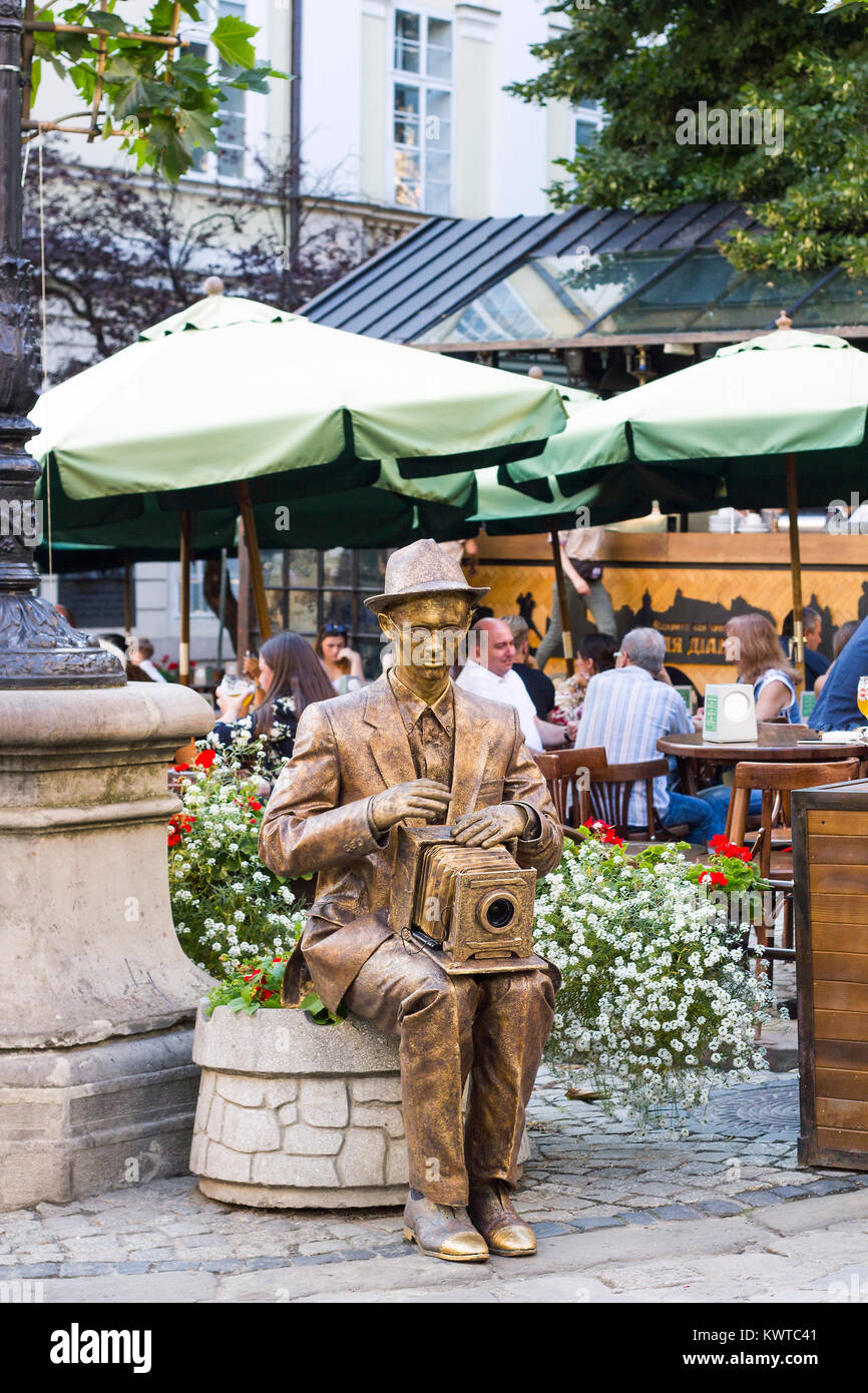 Lviv, Ukraine - le 22 juillet 2017 : gold statue photographe avec appareil photo se trouve sur lit de fleur avec des fleurs, journée d'été sur la ville Banque D'Images