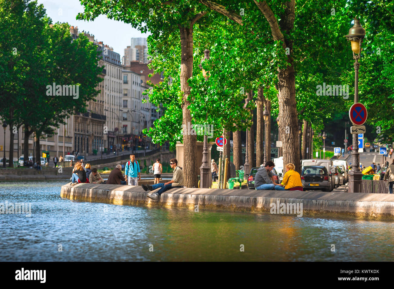 Printemps à Paris, vue sur les jeunes se reposant en fin de soirée de printemps le long de la bankment du Canal Saint-Martin dans le centre de Paris, France. Banque D'Images