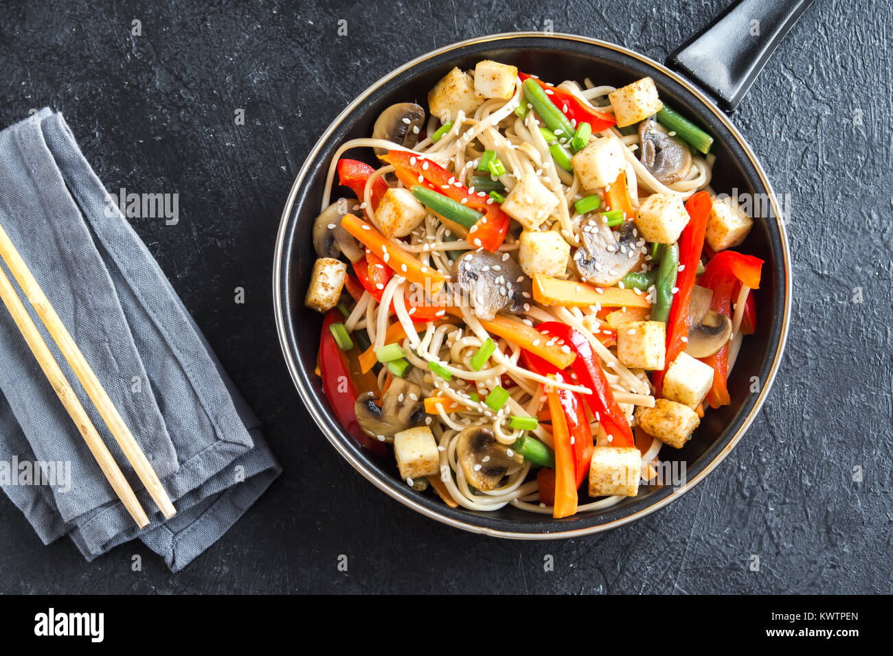 Faire revenir avec les nouilles Udon, tofu, champignons et légumes. La nourriture végétarienne, végétalienne asiatique, repas sautés au wok à fond noir, copiez l'espace. Banque D'Images