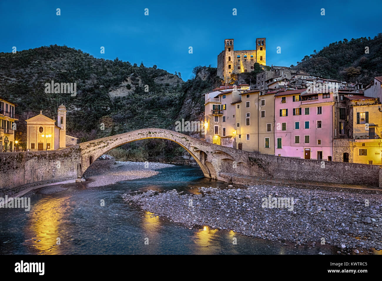 Dolceacqua ville au crépuscule, Ligurie, Italie, 15e siècle pont roman (Ponte Vecchio), au cours de la Nervia creek, maisons colorées et les ruines de la 13e Banque D'Images