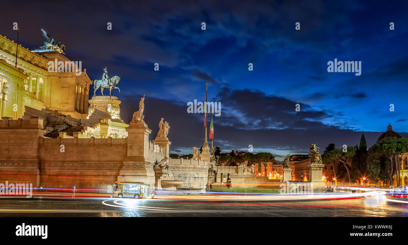 Monument célèbre de Rome à la tombée de la voiture avec légèreté dans l'foregroung crème glacée et d'un van. Le ciel est bleu profond et partiellement nuageux. Banque D'Images