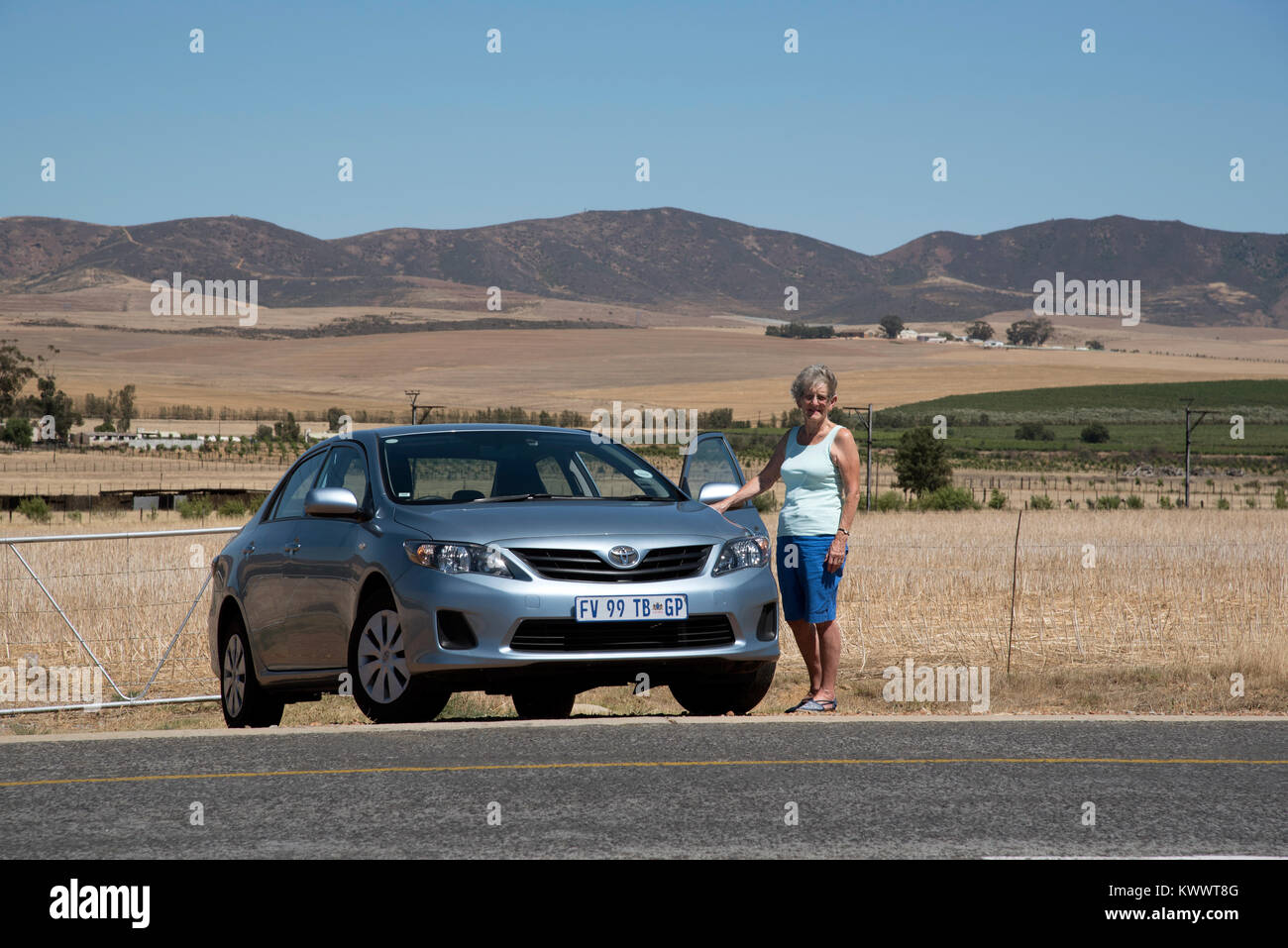 Région de l'Afrique du Sud, Orothamnus zeyheri. Décembre 2017. Femme debout avec une voiture de location au bord de la route Banque D'Images Région de l'Afrique du Sud, Orothamnus zeyheri. Décembre 2017. Femme debout avec une voiture de location au bord de la route Banque D'Images