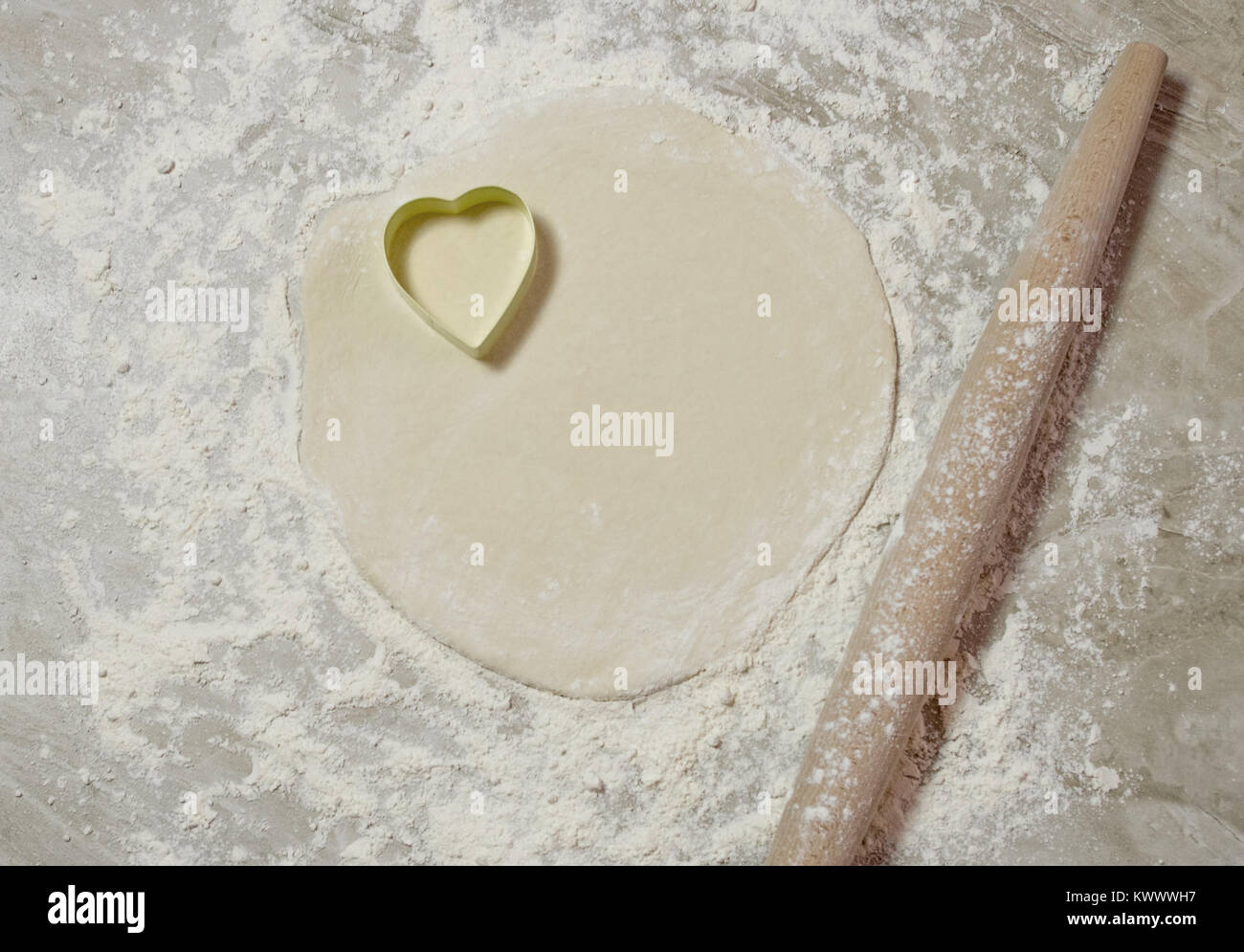 Emporte-pièce en forme de coeur sur la pâte avec un rouleau à pâtisserie Banque D'Images