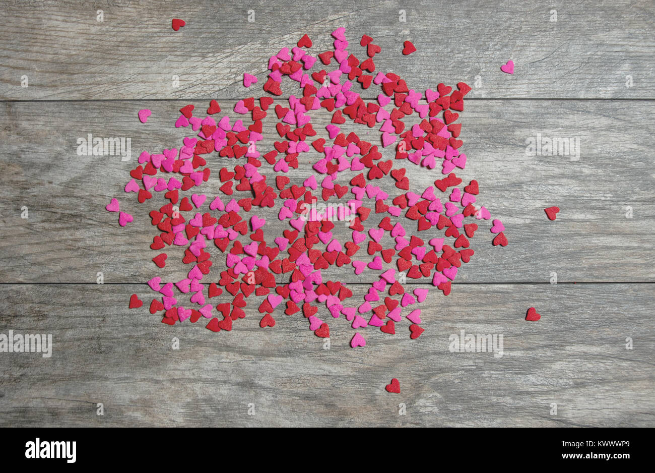 Roses et rouges éparpillées sur bonbons coeur un fond en bois Banque D'Images