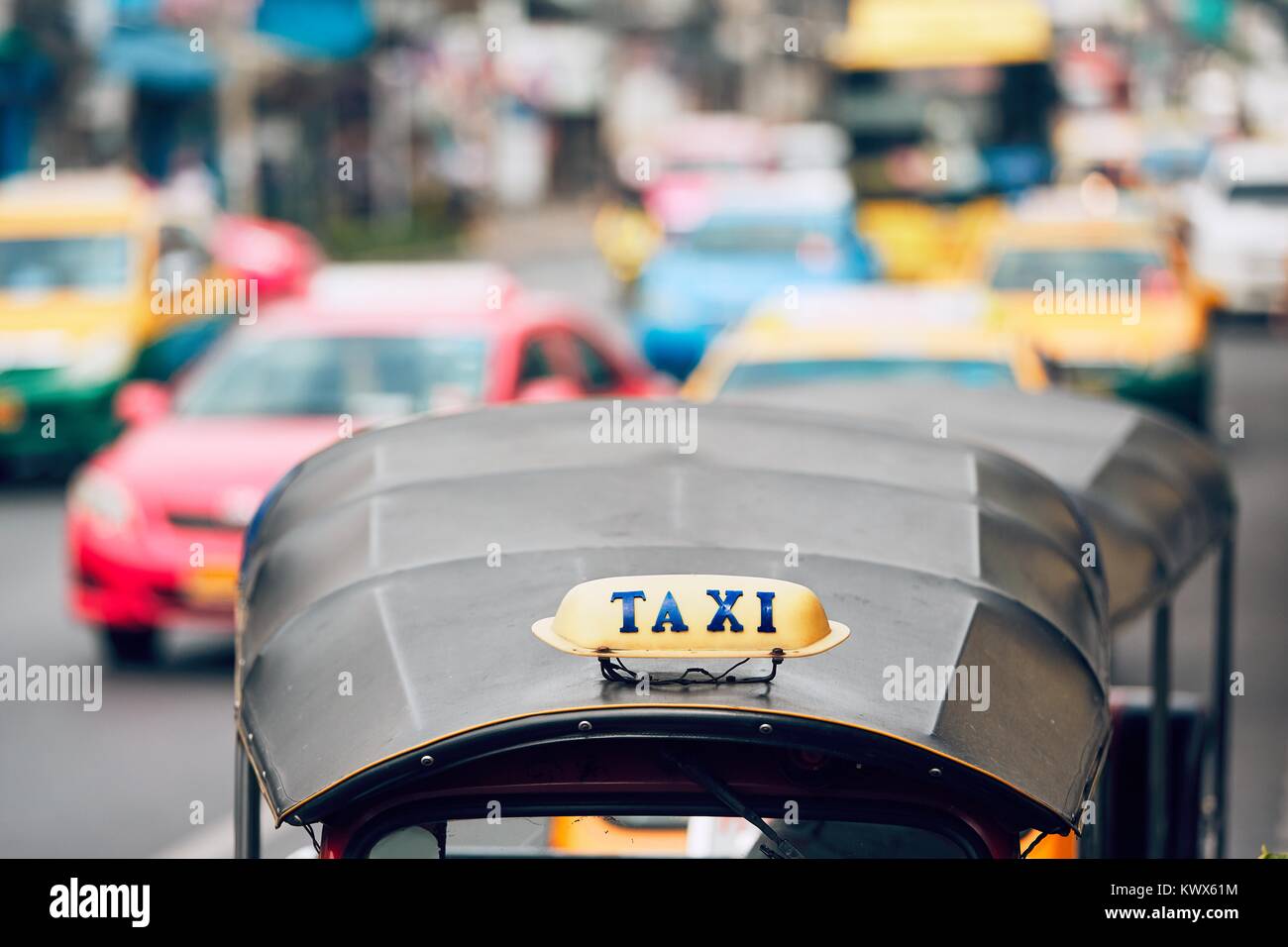 Enseigne sur le tuk tuk contre le trafic avec des voitures de taxi. Rue animée de Bangkok, Thaïlande Banque D'Images