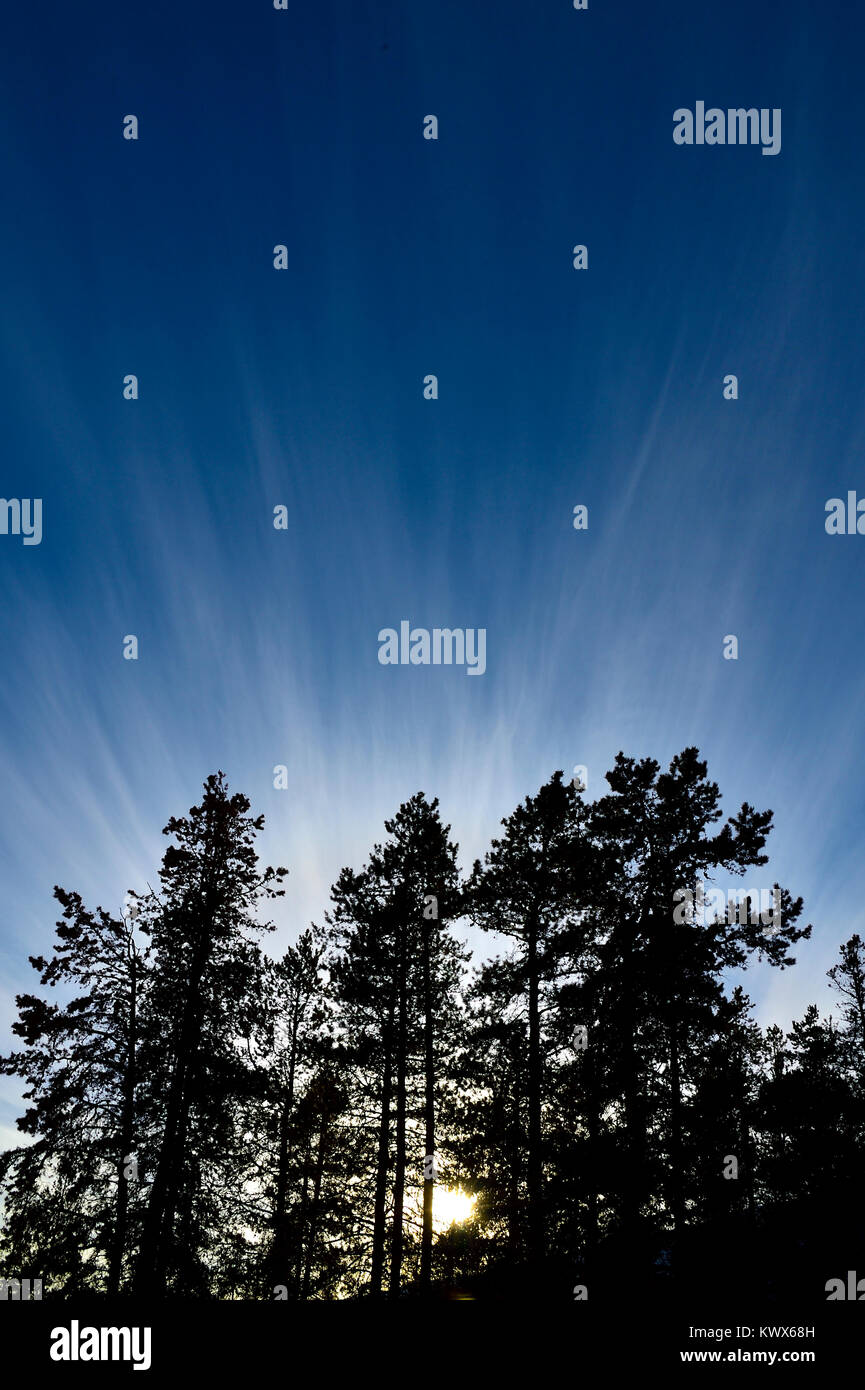 Une verticale de l'image du soleil couchant en faisceaux de lumière briller au-dessus d'une montagne dans le parc national Jasper, Alberta, Canada. Banque D'Images