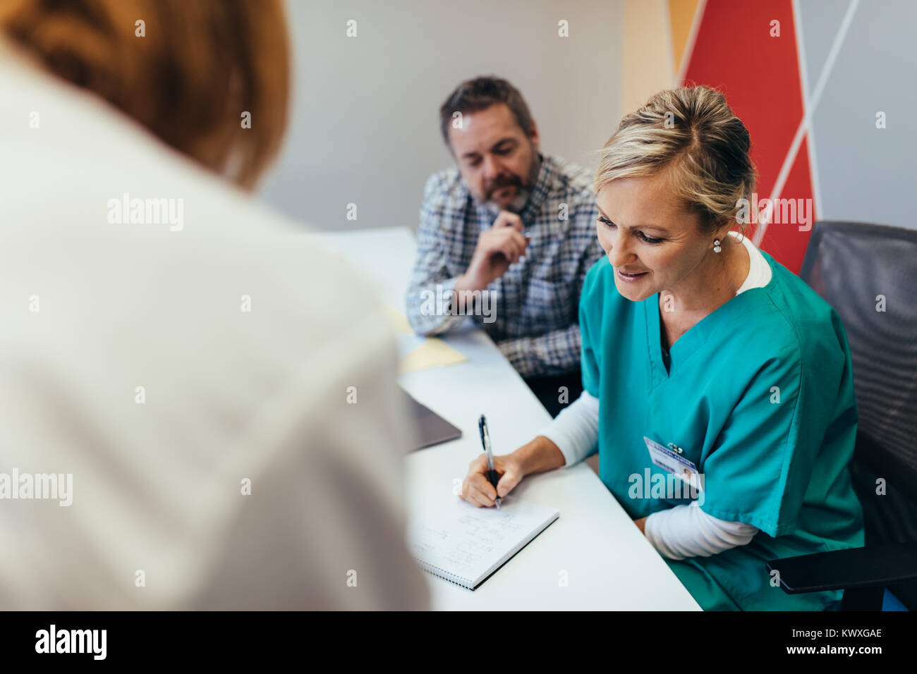 Infirmière assis en réunion avec vos collègues et la rédaction de notes. L'équipe des travailleurs de la santé dans la salle de réunion à l'hôpital. Banque D'Images