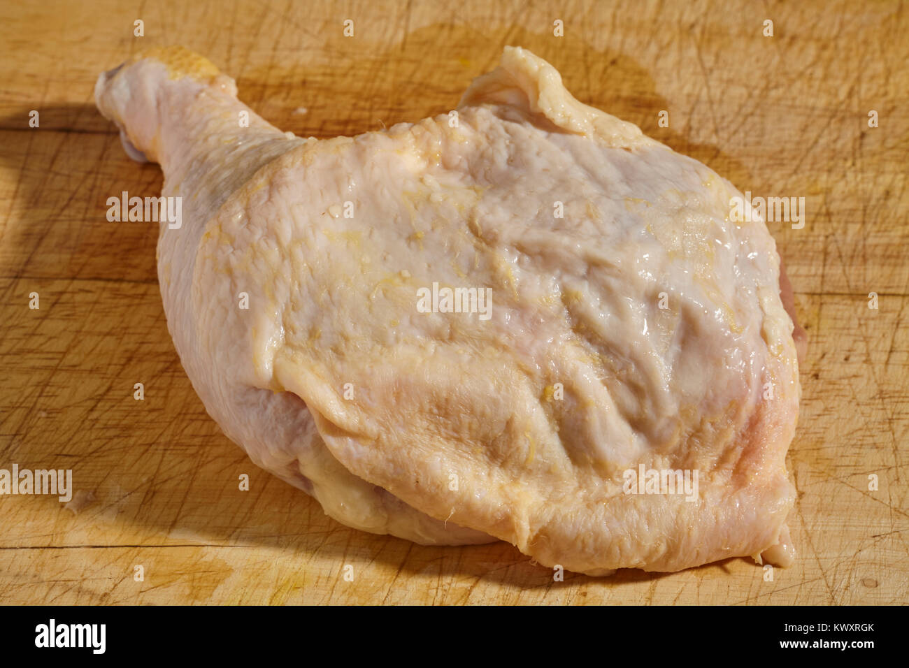 Jambe et la cuisse de poulet crue sur un bloc de boucher en bois Banque D'Images