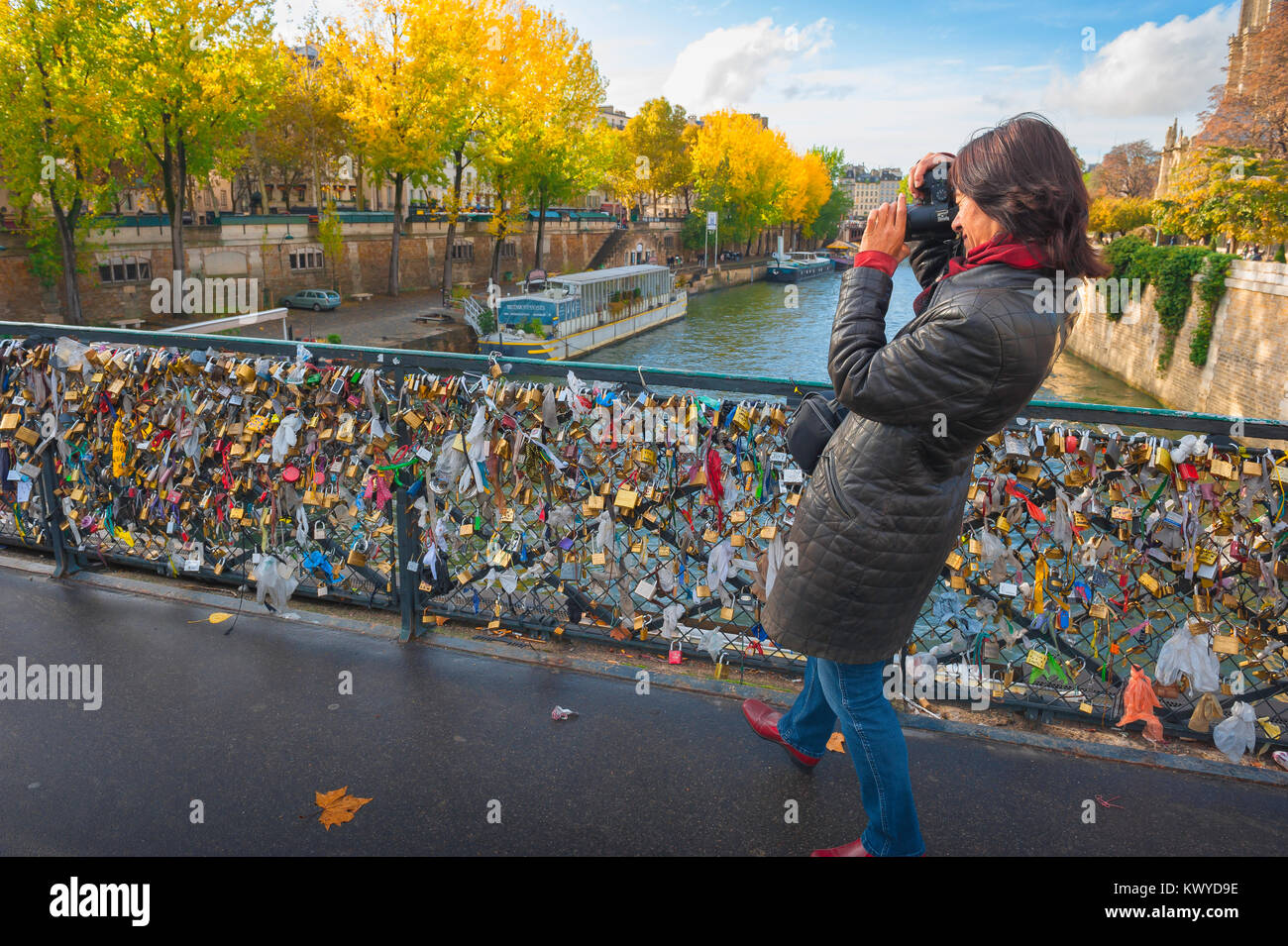 Paris touriste Seine, vue en automne d'une touriste féminine prenant une photo des écluses d'amour attachées au Pont de l'Archeveche à Paris, France. Banque D'Images