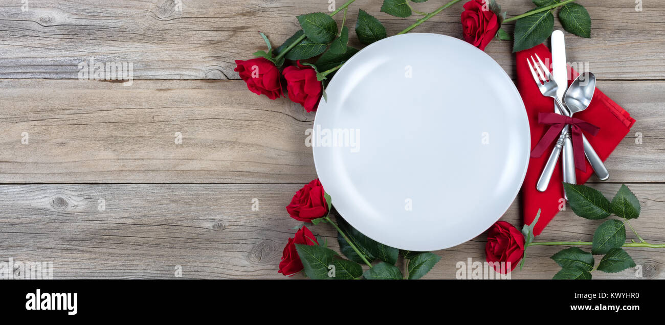 Appartement de vacances pour le dîner avec des roses rouges et de l'argenterie sur bois rustique en vue mise à plat Banque D'Images
