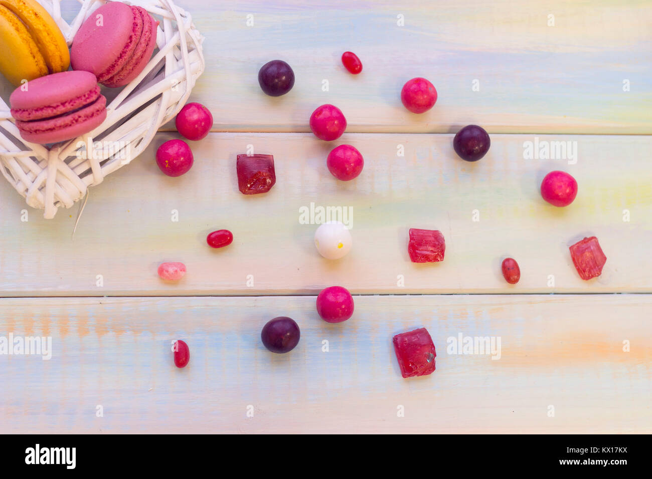 Une couronne de coeur tissé blanc aux fruits frais macarons et bonbons colorés éparpillés sur la table. L'espace pour votre texte ou image sur la gauche. Saint Valen Banque D'Images