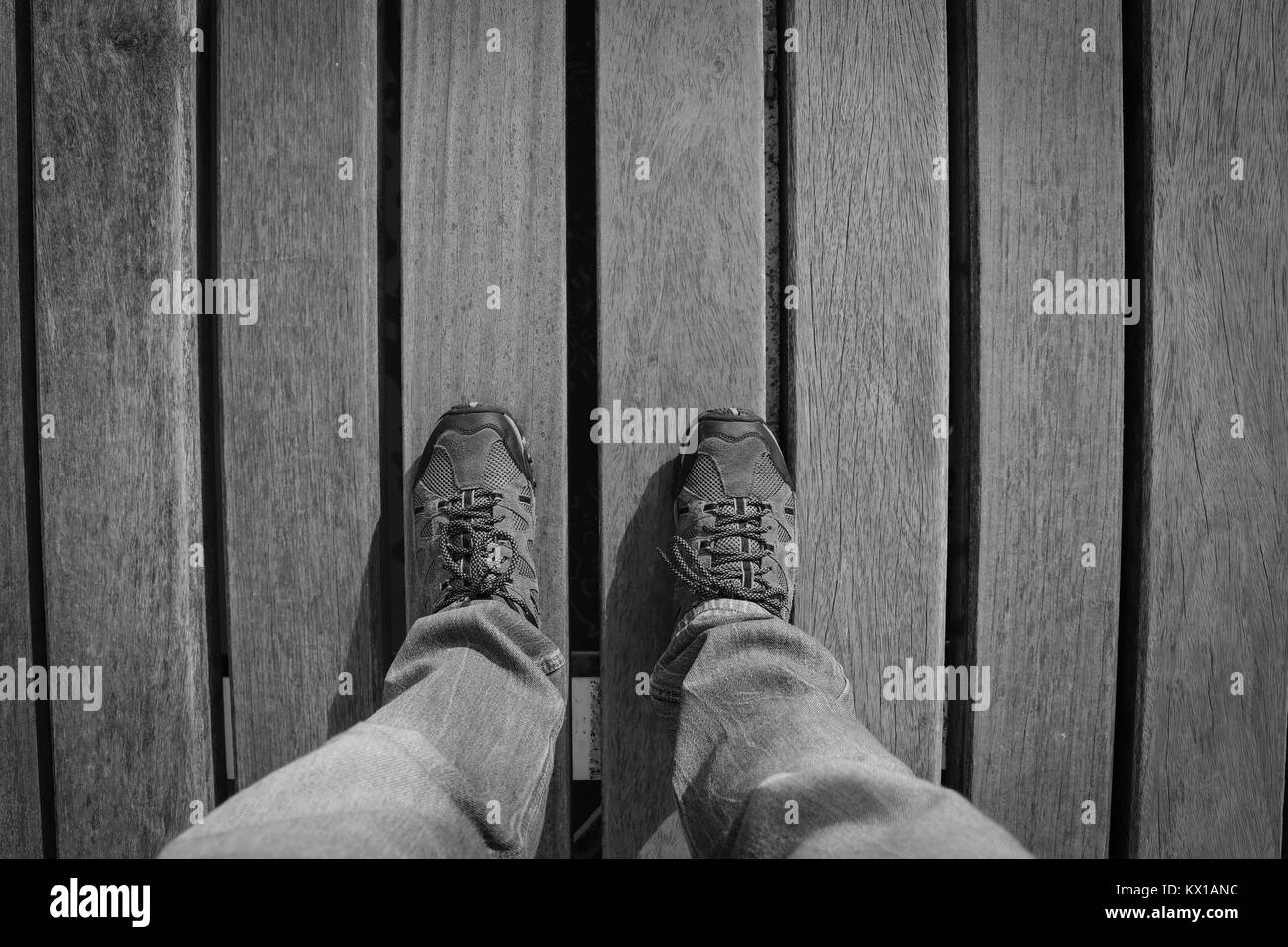 Vue de dessus de jeune homme avec des baskets et jeans dans un plancher de bois. Chaussures d'aventure. Banque D'Images