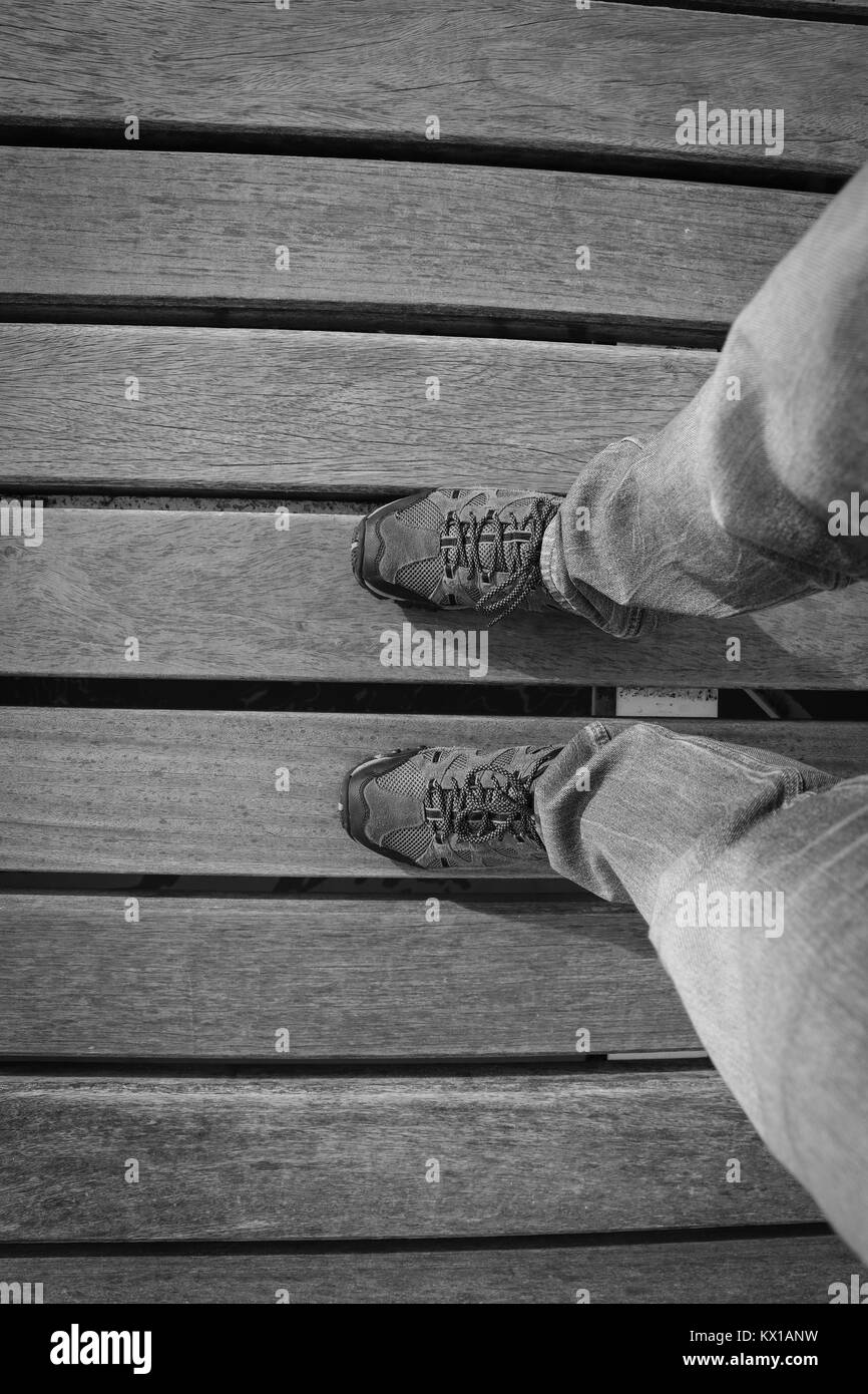 Vue de dessus de jeune homme avec des baskets et jeans dans un plancher de bois. Chaussures d'aventure. Banque D'Images